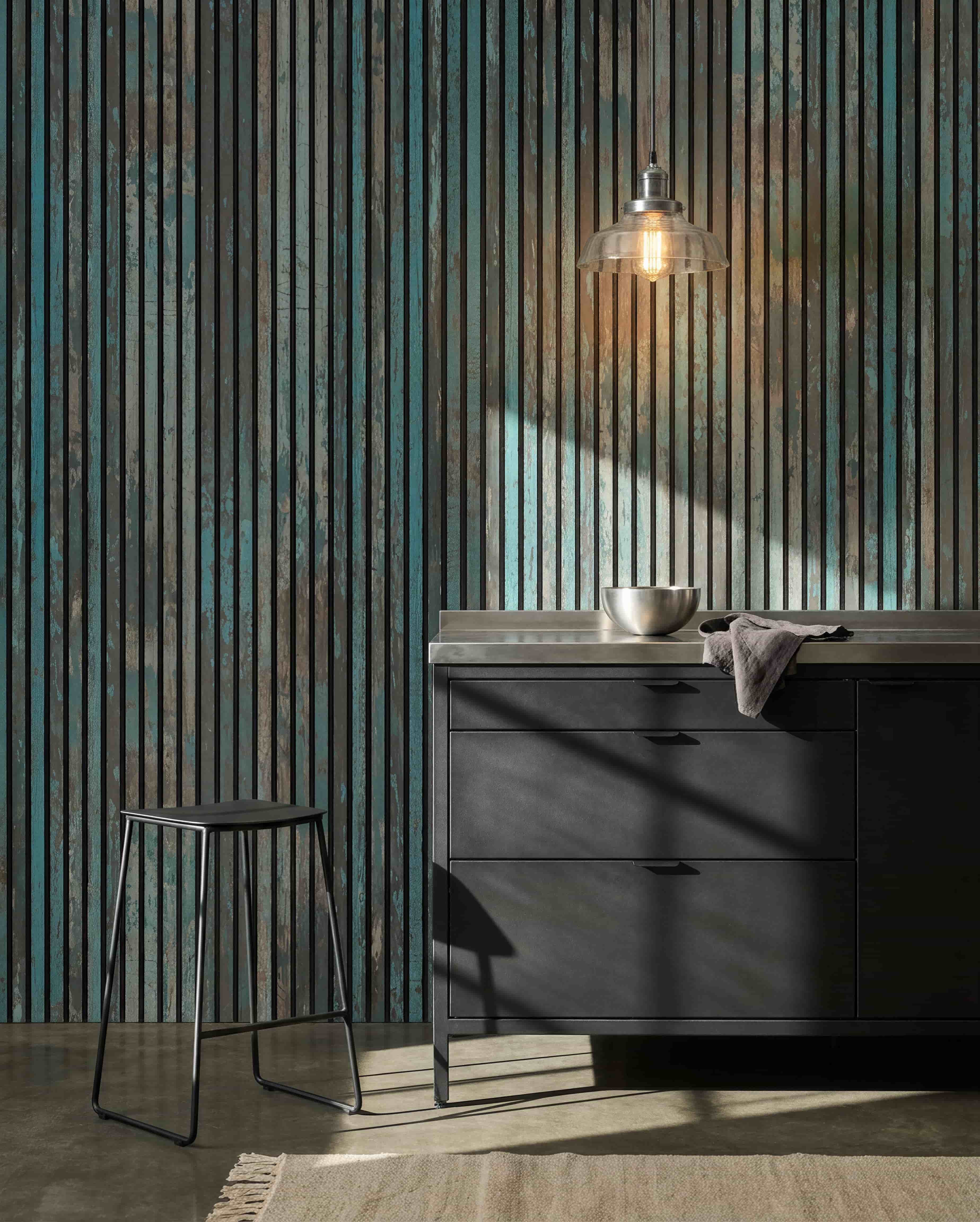 Moderne Küche mit black Hockern, black Schränken, einer Schale unter einer Glühbirnenleuchte und einem WoodUpp Akupanel Oxide Blue Akustikpaneel an der Wand für akustischen Komfort.