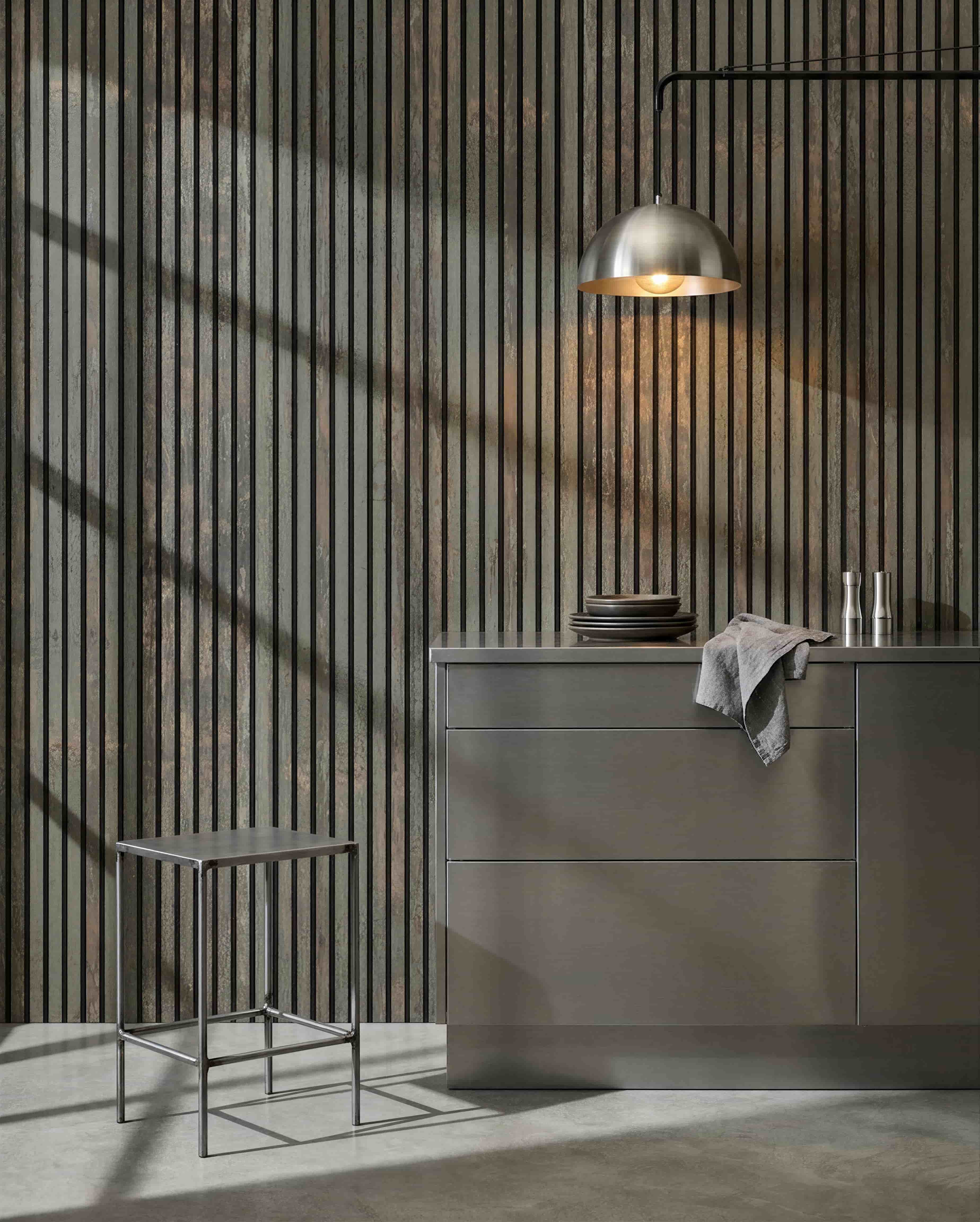 Minimalistische Küche mit Metallhocker, grey Kücheninsel und Geschirr, mit einem WoodUpp Akupanel Akustikholzpaneel in Oxide Grey/Black Felt zur Schallkontrolle.