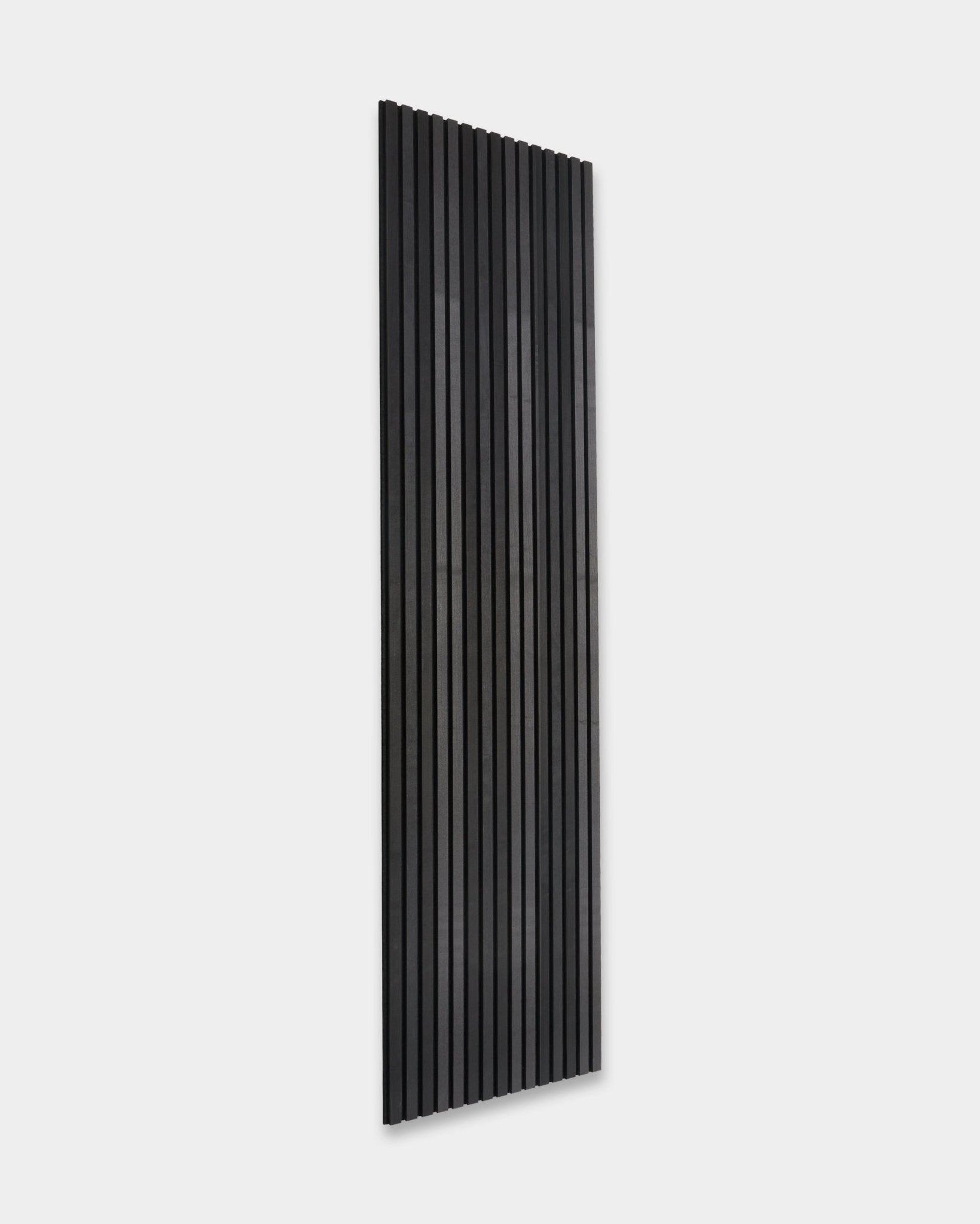 WoodUpp Akupanel Tonal Akustikpaneel in Black Ash (300x60cm) mit vertical Lamellen, montiert an einer schlichten hellgrauen Wand, zeigt minimalistisches skandinavisches Design.