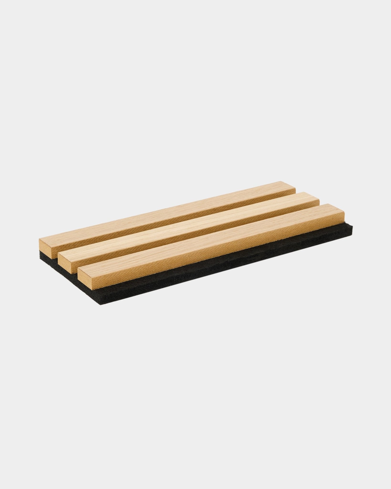 Das WoodUpp Akupanel Mustertablett in Classic Oak zeigt drei Akustik-Holzlamellen auf einer Filzbasis aus black und bringt nordisches Design sowie den Kontrast der Materialien zur Geltung.
