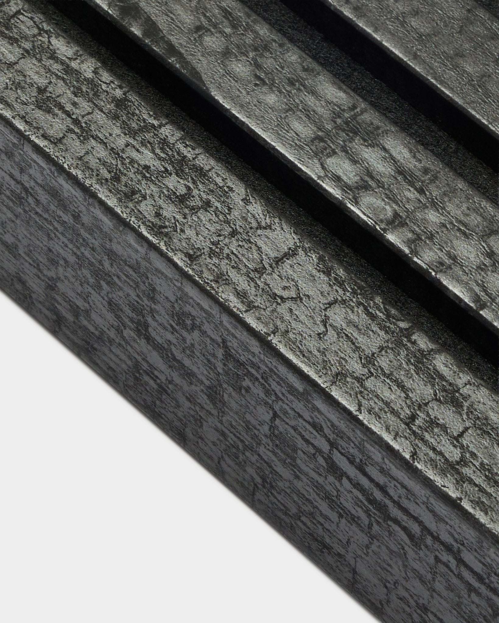 Nahaufnahme der WoodUpp Akupanel Endlamelle in Charcoal, 6,7 cm breit, mit parallelen Akustiklamellen und markanter Holzmaserung.