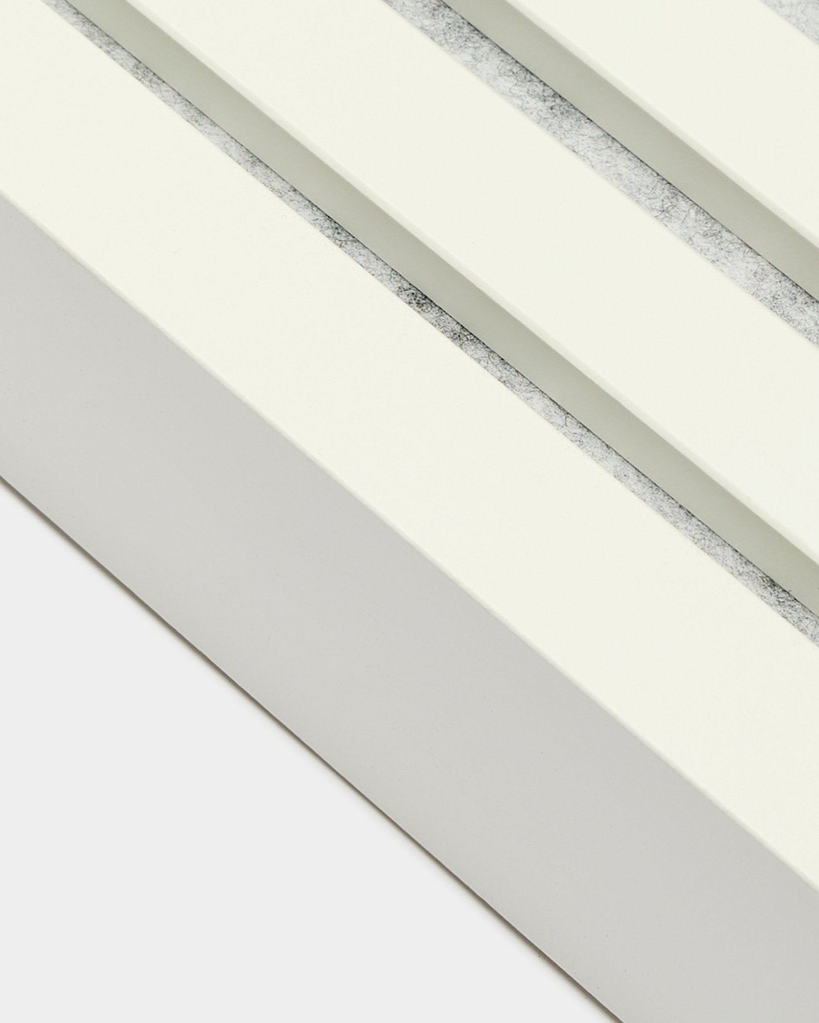 Nahaufnahme der WoodUpp Endlamelle in Snow, 6,7 cm breit, mit MDF-Rahmen, doppelten Nuten und einer strukturierten Oberfläche in grey für die Akupanel Akustikpaneel-Installation.