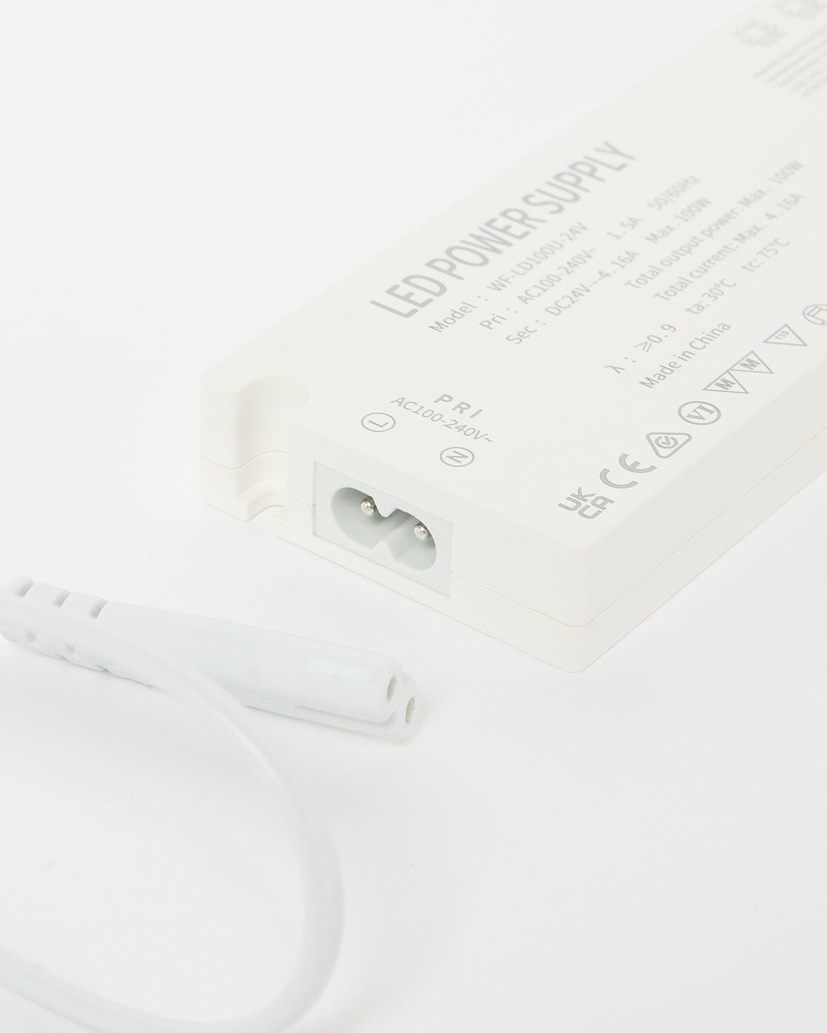 Nahaufnahme eines Netzteils für beige WoodUpp Lumi LED-Lichtleisten (240 cm) mit technischen Details und danebenliegendem Kabel, ausgelegt für nordische Akustikpaneel Installationen.