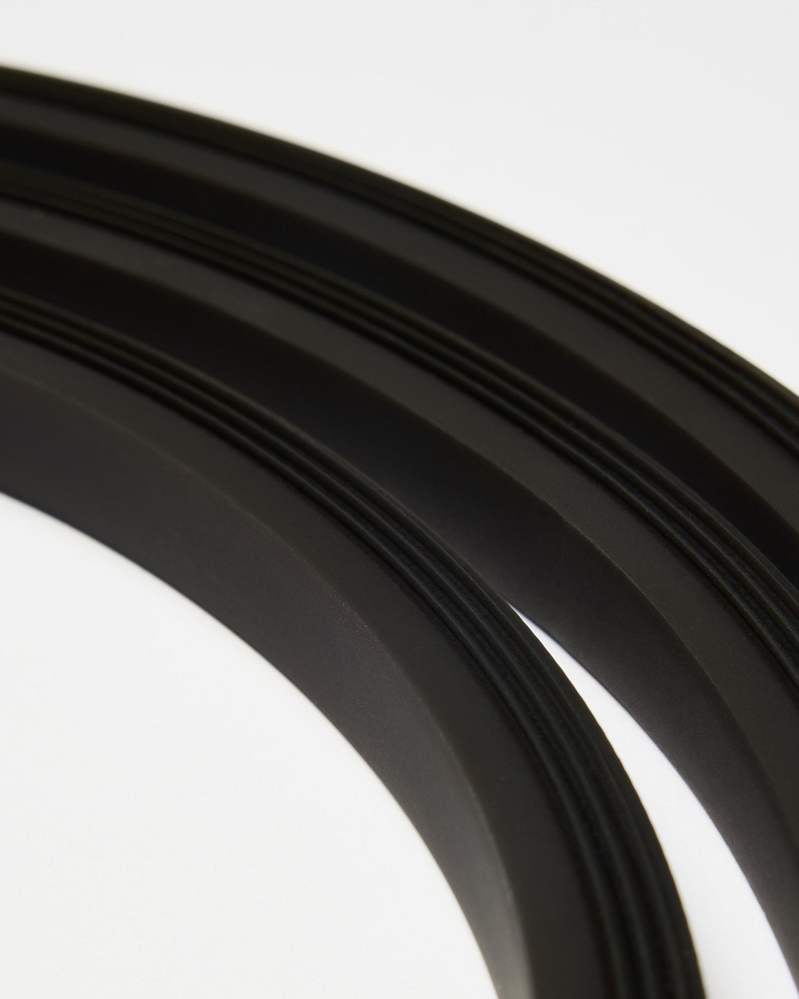 Nahaufnahme der black Lumi LED-Lichtleiste von WoodUpp (300 cm), in geschwungenen Linien auf Weiß arrangiert, passend zum minimalistischen Akupanel Akustikpaneel Stil.