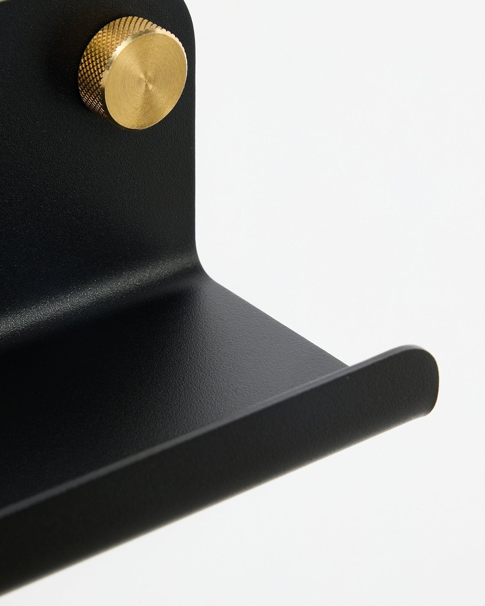 Nahaufnahme der WoodUpp Norr Schmalen Ablage in black, 75,9 cm, mit einem goldfarbenen Knauf mit strukturierter Oberfläche, vor weißem Hintergrund.