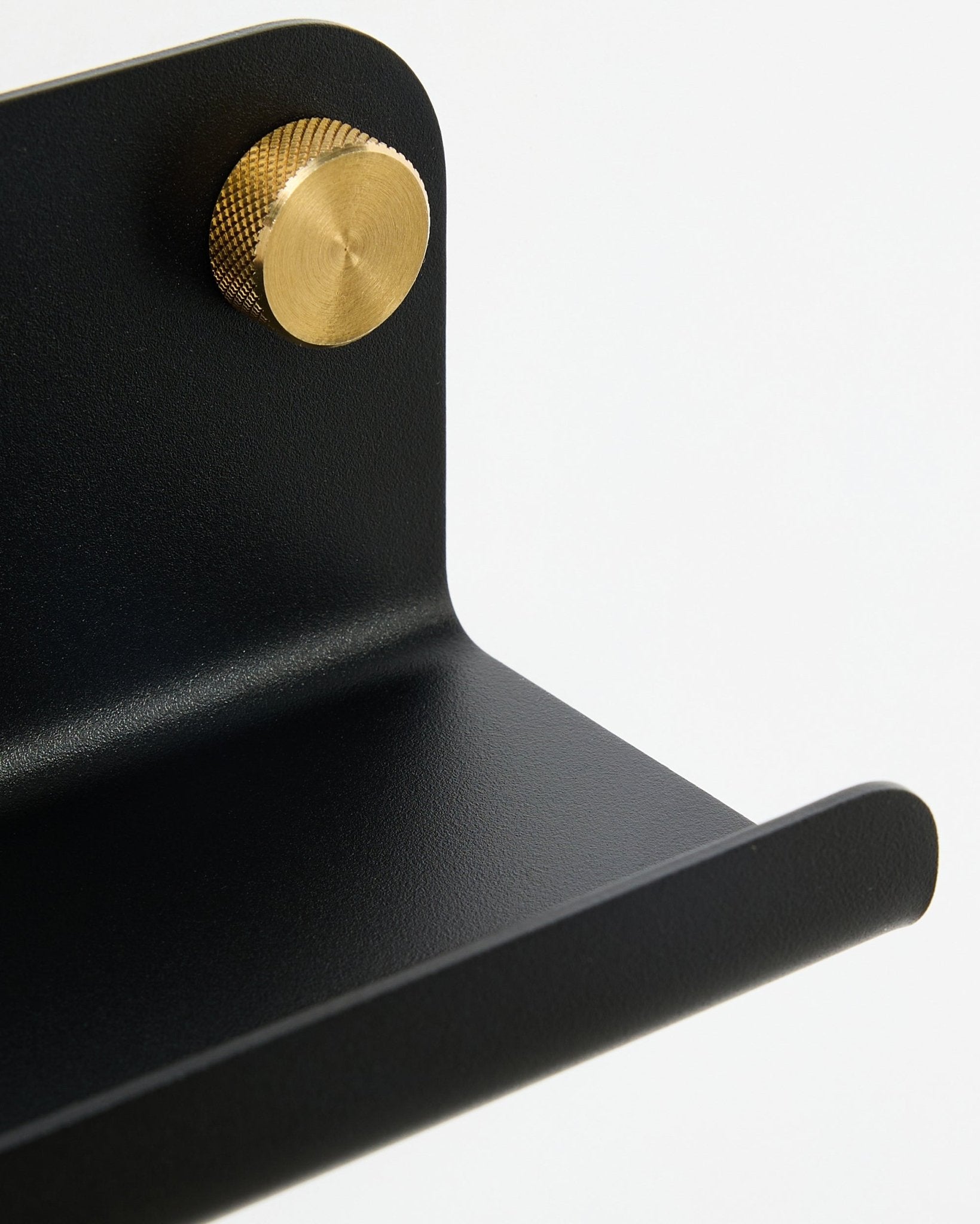 Nahaufnahme des WoodUpp Norr Narrow Shelf, 35,9 cm, black steel mit geschwungener Kante und goldenem Knopf, vor weißem Hintergrund.