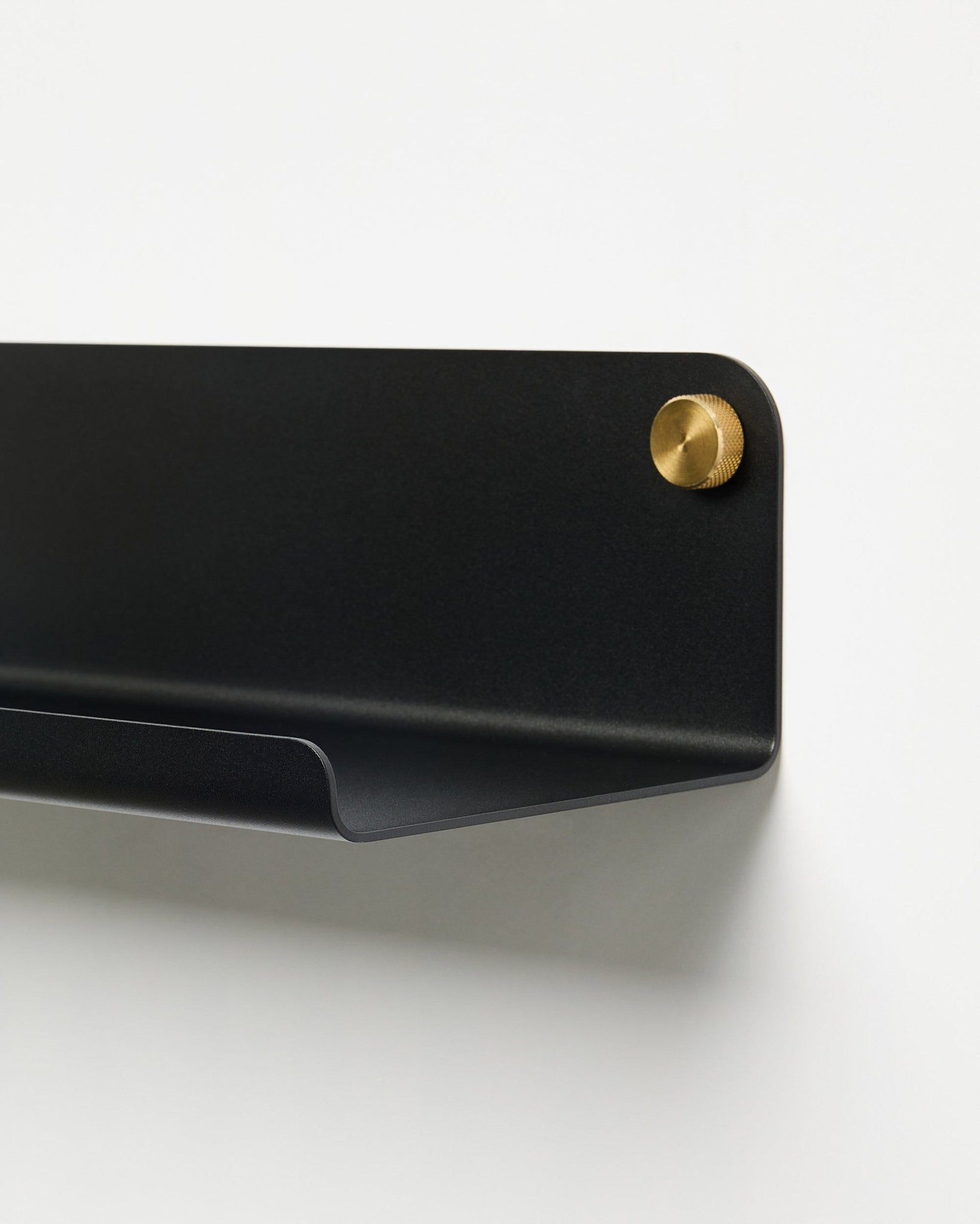 Nahaufnahme des WoodUpp Norr Wide Shelf (51,9 cm) Accessoires aus pulverbeschichtetem black Metall mit goldener Schraube, vor einem schlichten weißen Hintergrund.