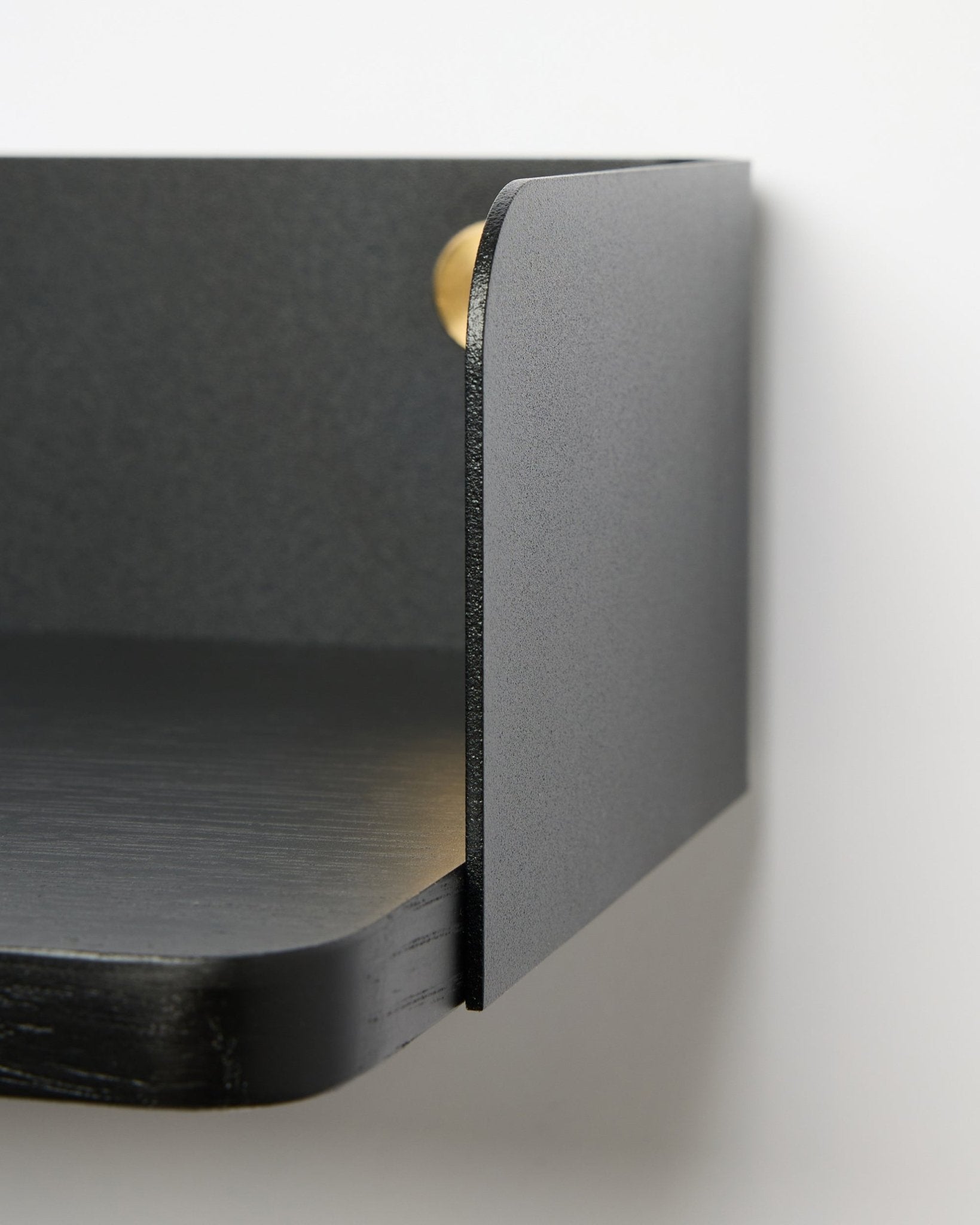 Nahaufnahme des WoodUpp Linn Bücherregals in Black Oak, 39,9 cm breit, mit abgerundeten Kanten und matter Oberfläche, montiert an einer weißen Wand. Nordischer minimalistischer Stil.