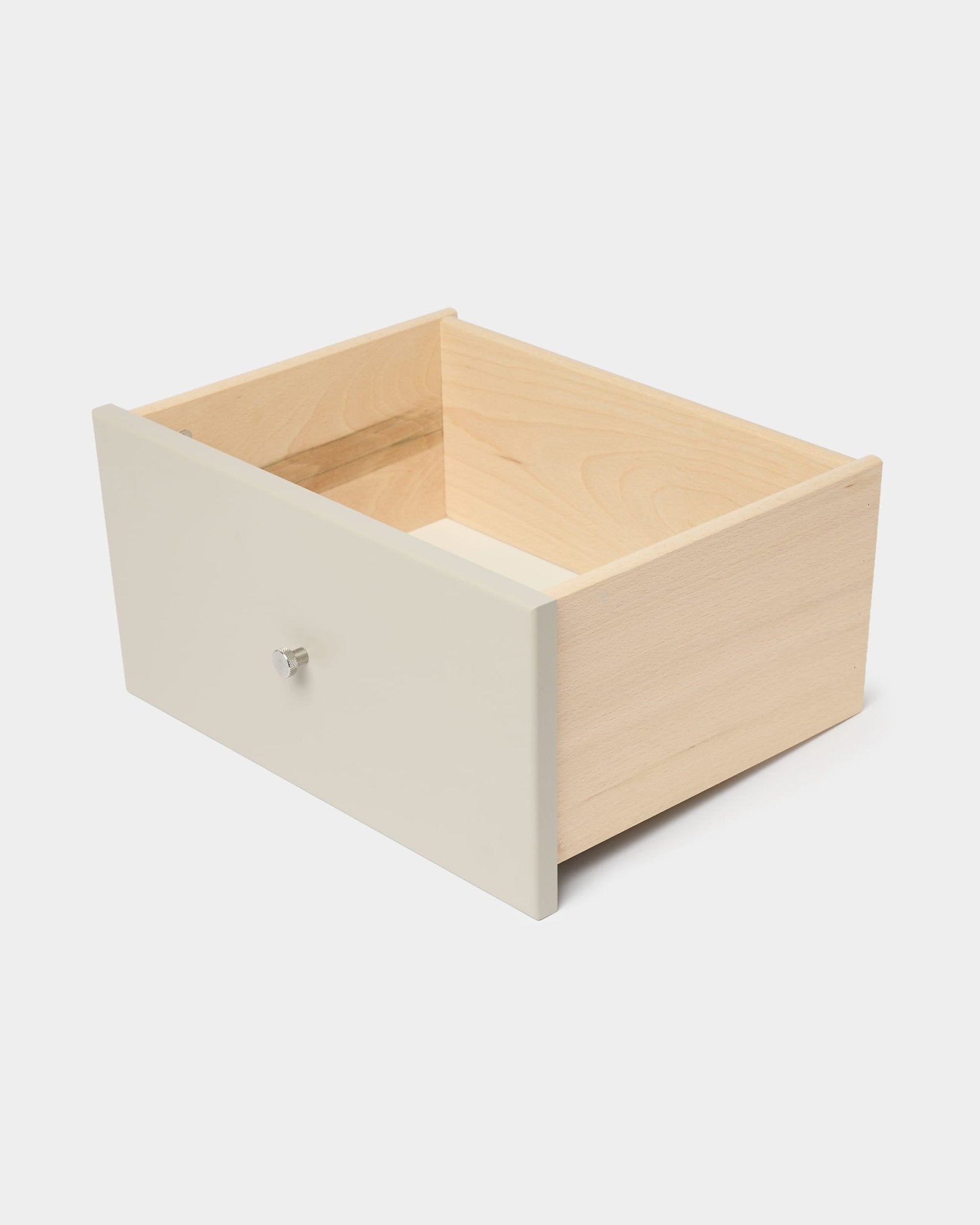 WoodUpp Arka Bücherregal-Schublade in Beige mit weißer Frontblende und weißem Knauf, konzipiert für die geschlossene Aufbewahrung, abgebildet vor einem schlichten weißen Hintergrund.