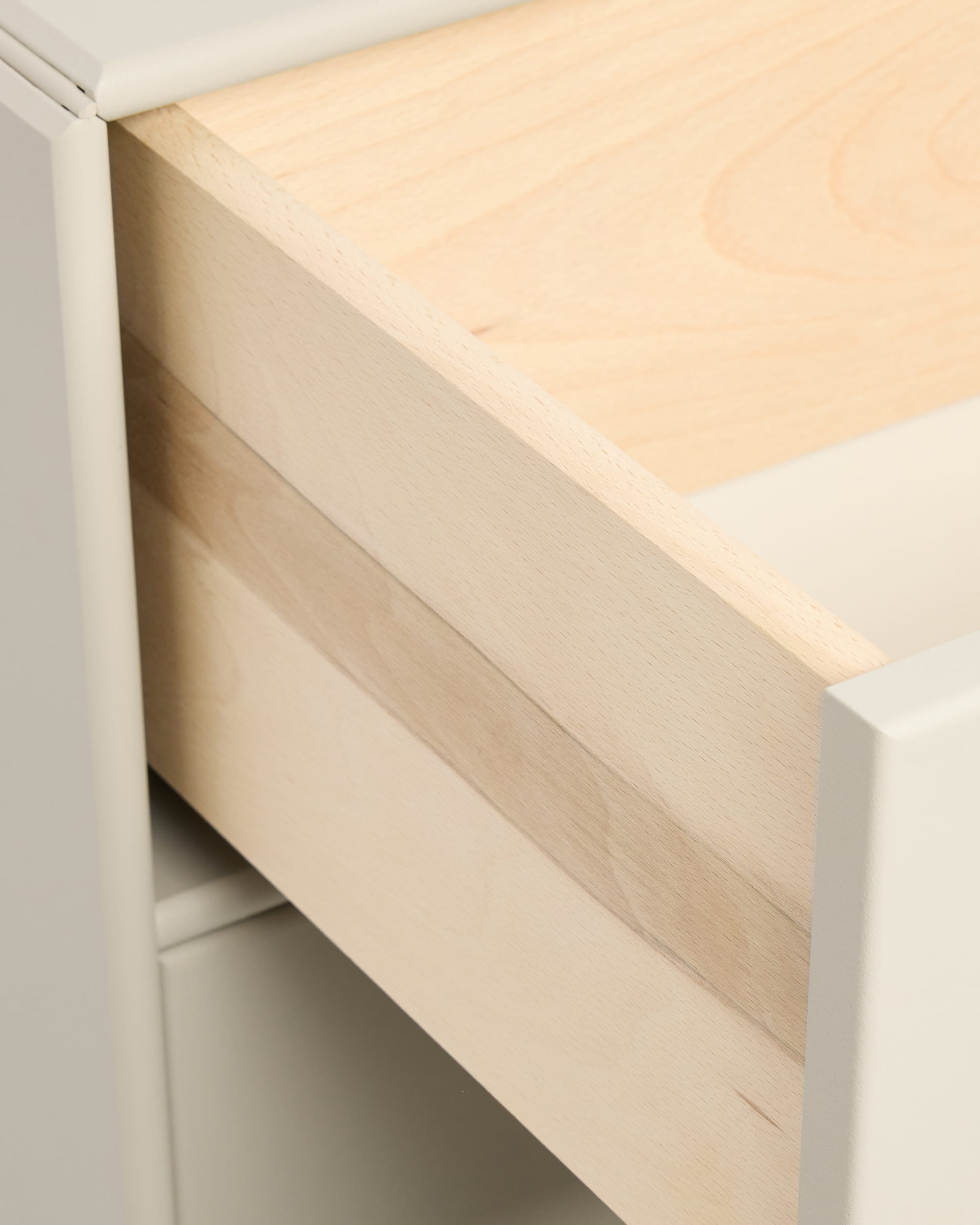 Nahaufnahme einer teilweise geöffneten, beigen „Arka“-Bücherregalschublade von WoodUpp in einem weißen Schrank, abgebildet mit Griffen aus der CREATE-Kollektion.