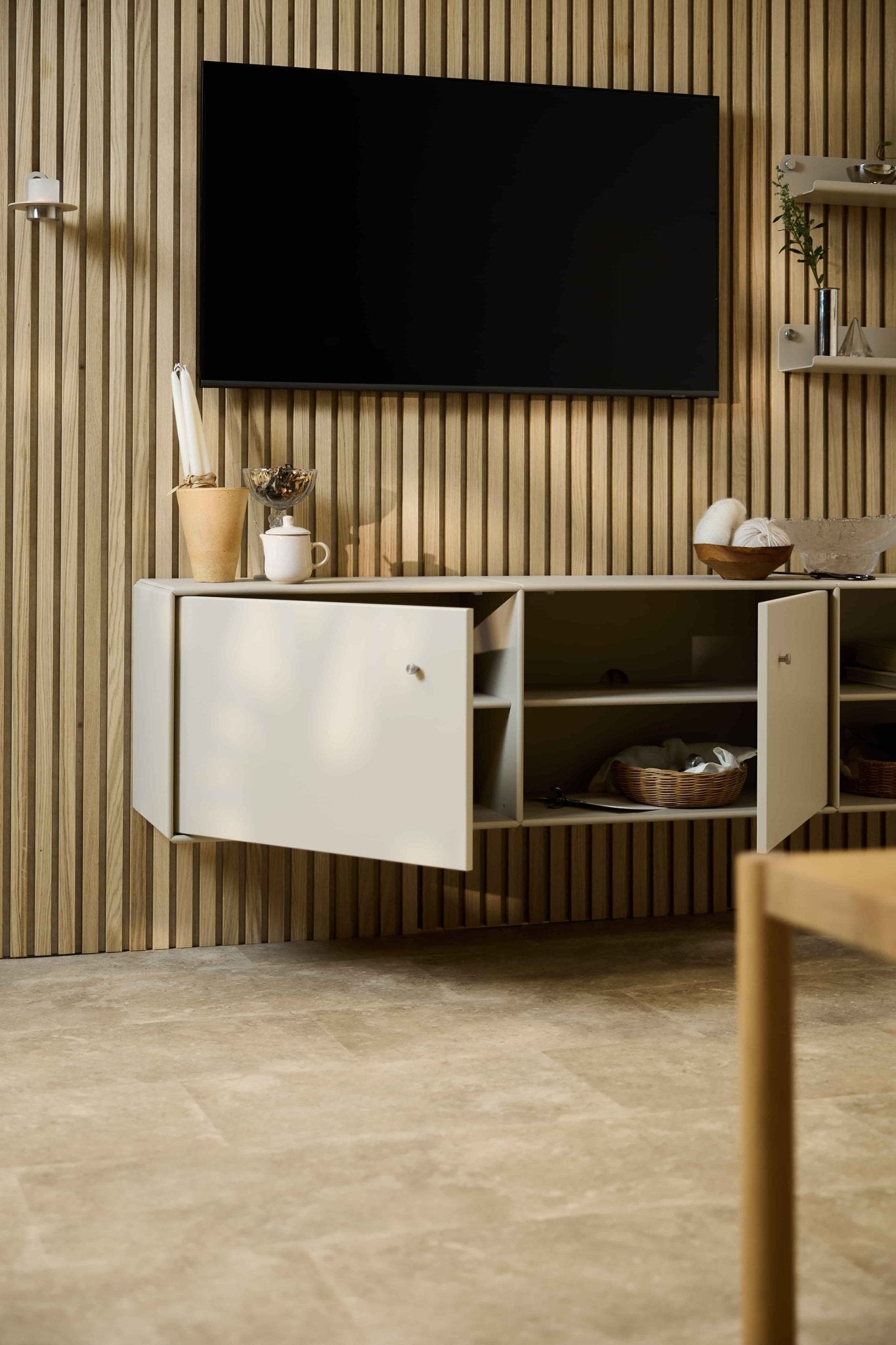 Modernes Wohnzimmer mit dem TV-Möbel „Arka“ in Beige von WoodUpp unter einem Schrank und einem Fernseher vor einer Akupanel-Akustikwand aus Holzlamellen im nordischen Stil. Modulare Möbel.