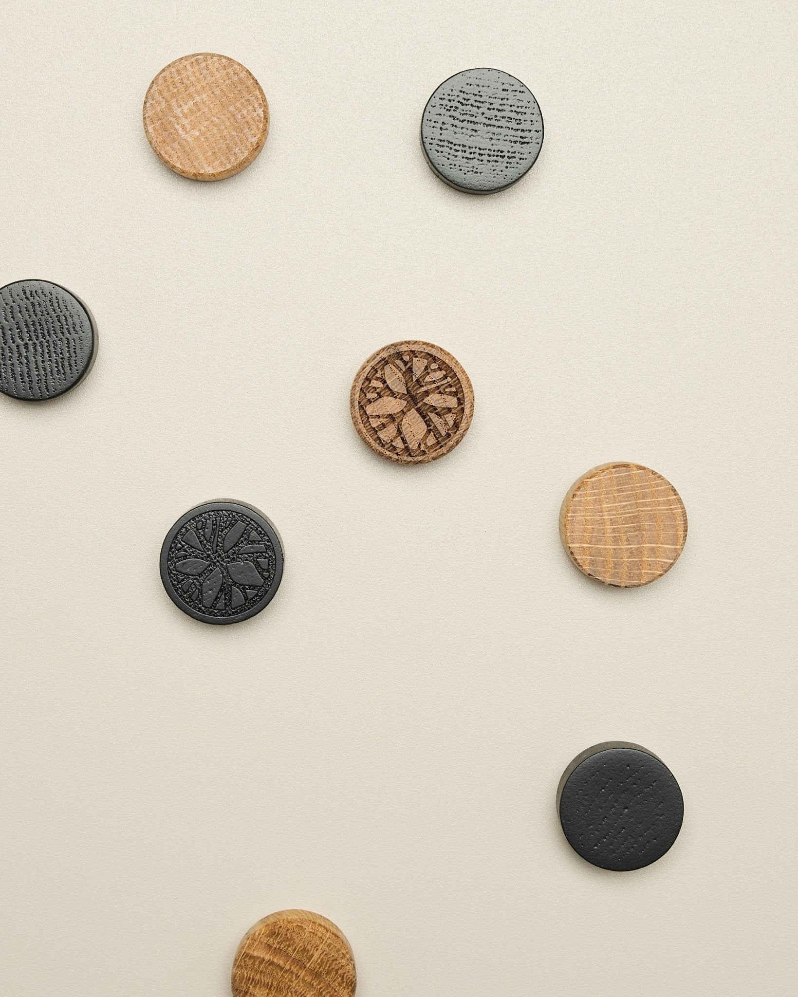 Das Norr Magnet-Set von WoodUpp umfasst vier Scheiben mit natural oak- und black-Muster, ordentlich auf einer hellen beige Oberfläche platziert; Zubehör für Akupanel.
