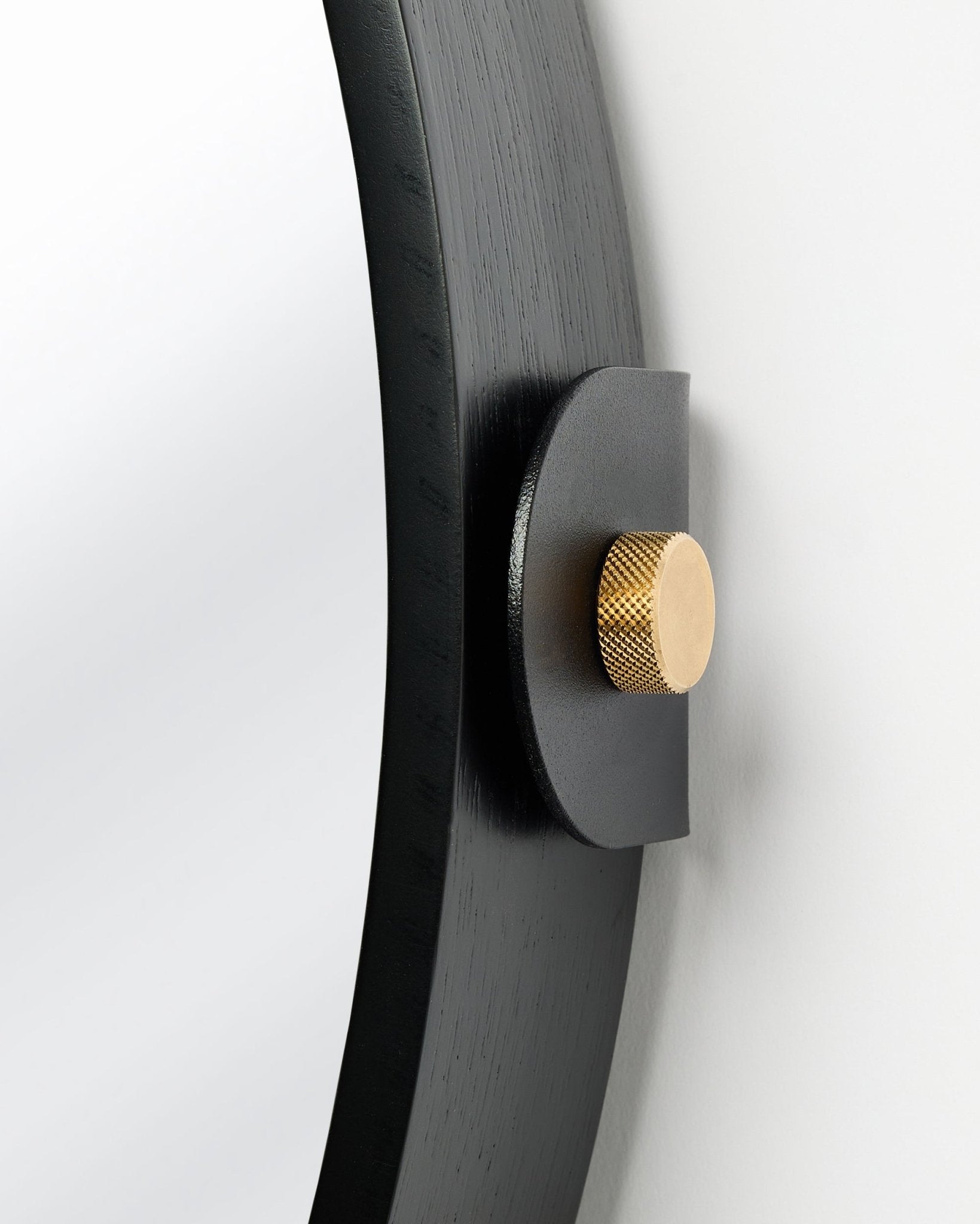 Detail der Linn | Mirror / Black Oak Akustikpaneel von WoodUpp, an der Wand montiert mit goldenem Knauf und verstellbarer Neigung.