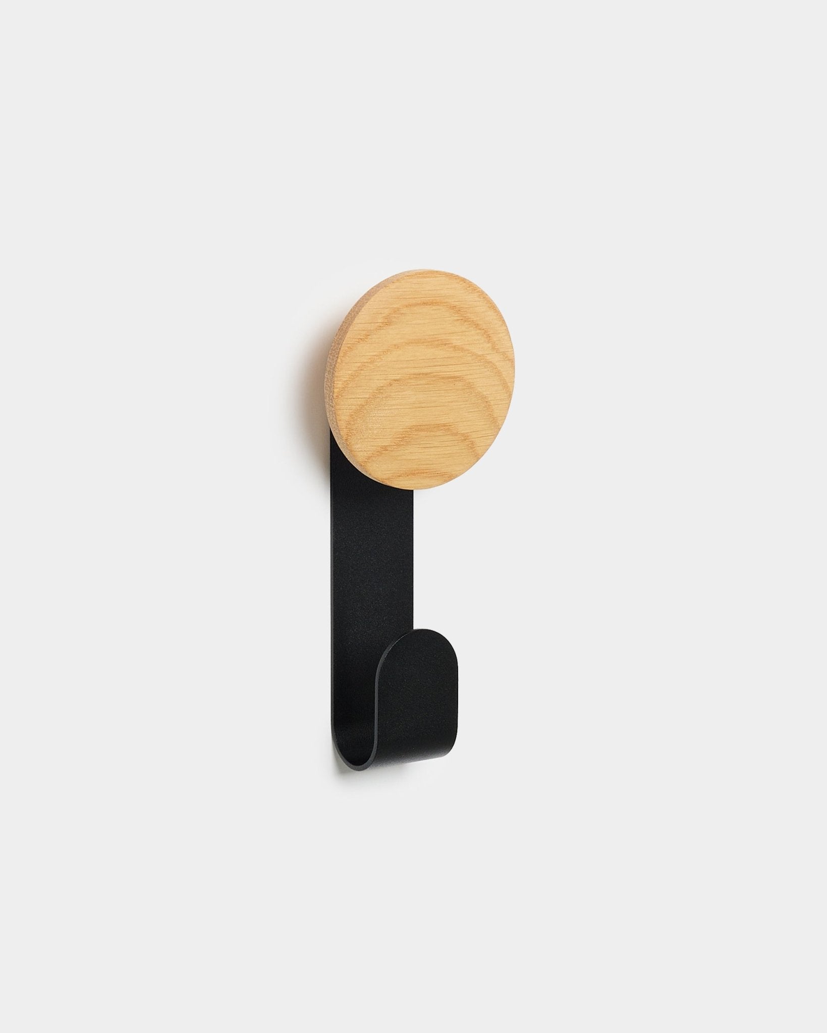 Der Linn Vertical Hanger von WoodUpp mit rundem natural oak Kopf und black Metallhaken wurde dafür entworfen, Accessoires an den Akupanels Nordic Akustikholzpaneelen aufzuhängen.