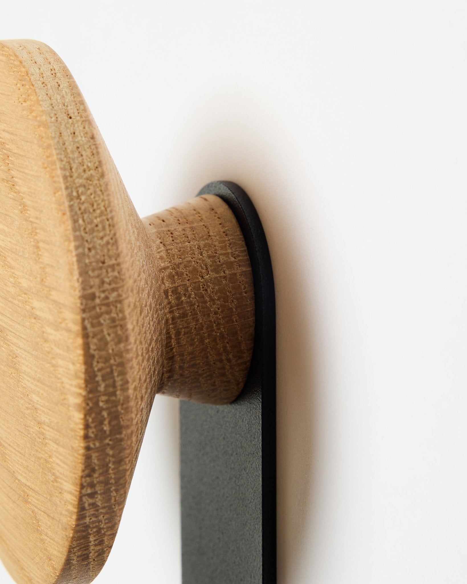 Nahaufnahme des Linn Vertical Hanger in natural oak von WoodUpp, ein Accessoire mit rundem Holzknauf, das auf einer black Halterung montiert ist und für Akupanel Akustikpaneele entworfen wurde.