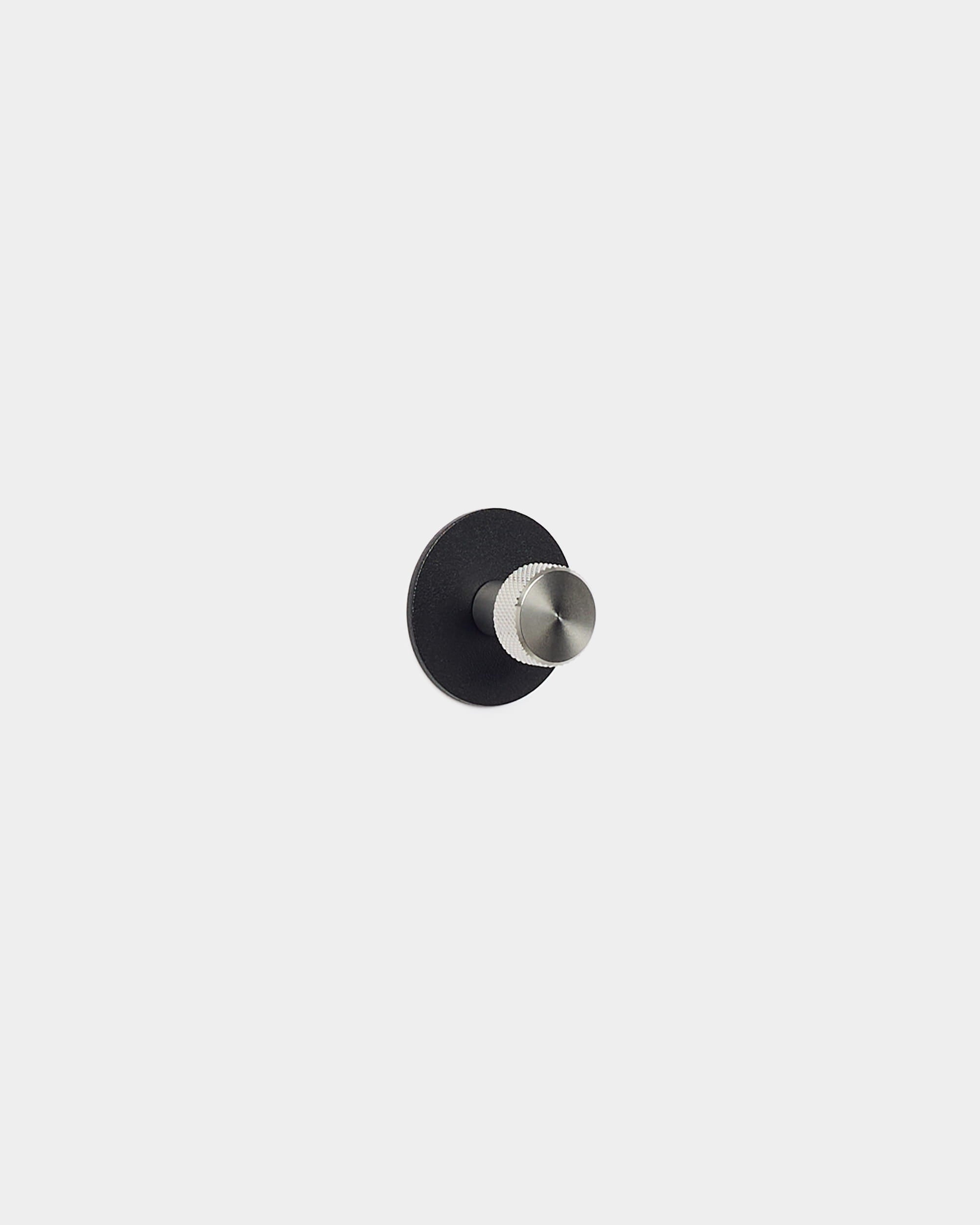 Der Norr Coat Hook von WoodUpp hat eine runde Basis aus black und einen silbernen Hakenstift. Er wurde als Zubehör für Akupanel Akustikpaneele entworfen und passt gut in minimalistische, nordische Räume.