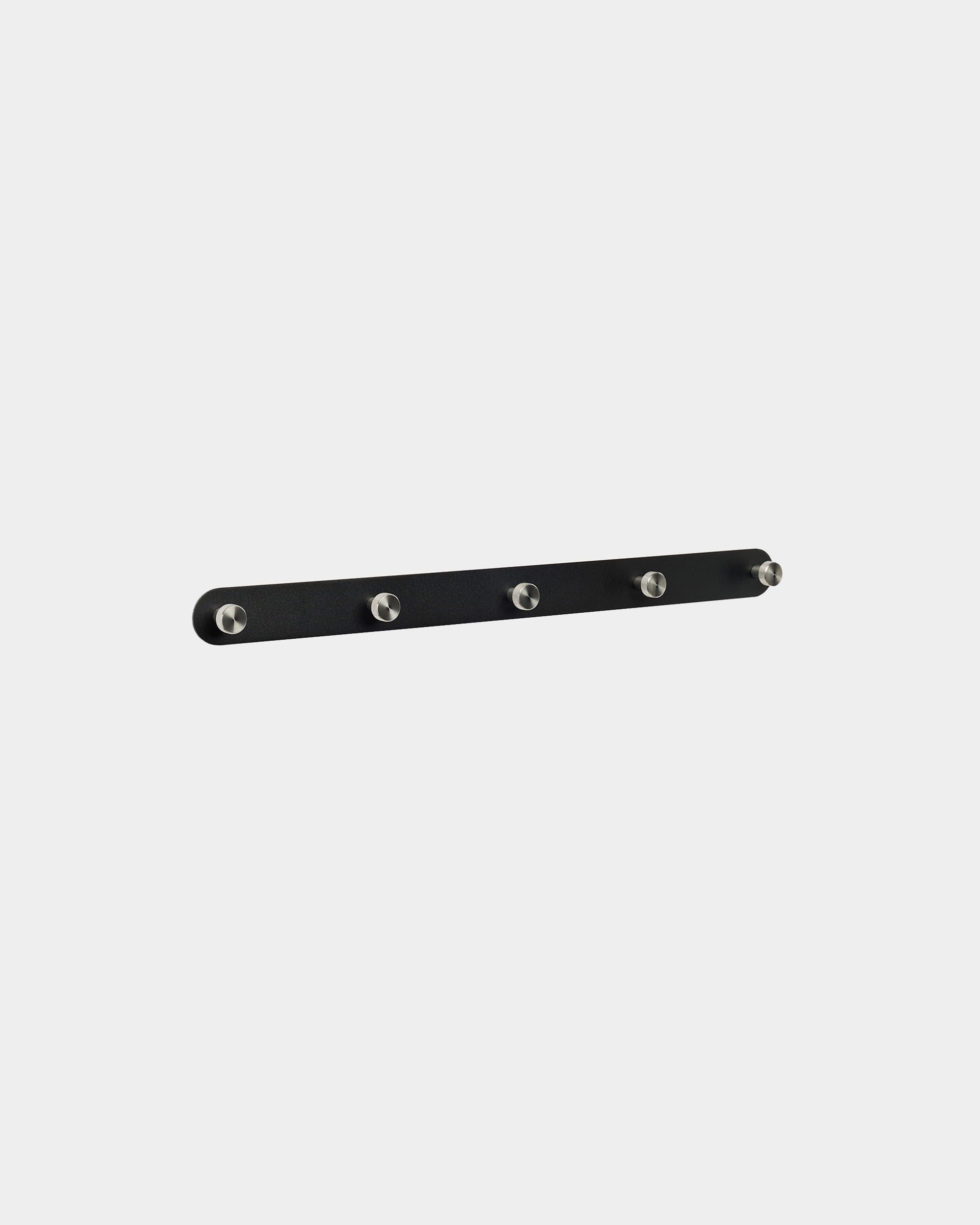 WoodUpp Norr Garderobenhakenleiste X5 in black und Edelstahl steel, mit fünf gleichmäßig angeordneten Haken, vor einem schlichten weißen Hintergrund montiert. Nordisch-minimalistisches Design.