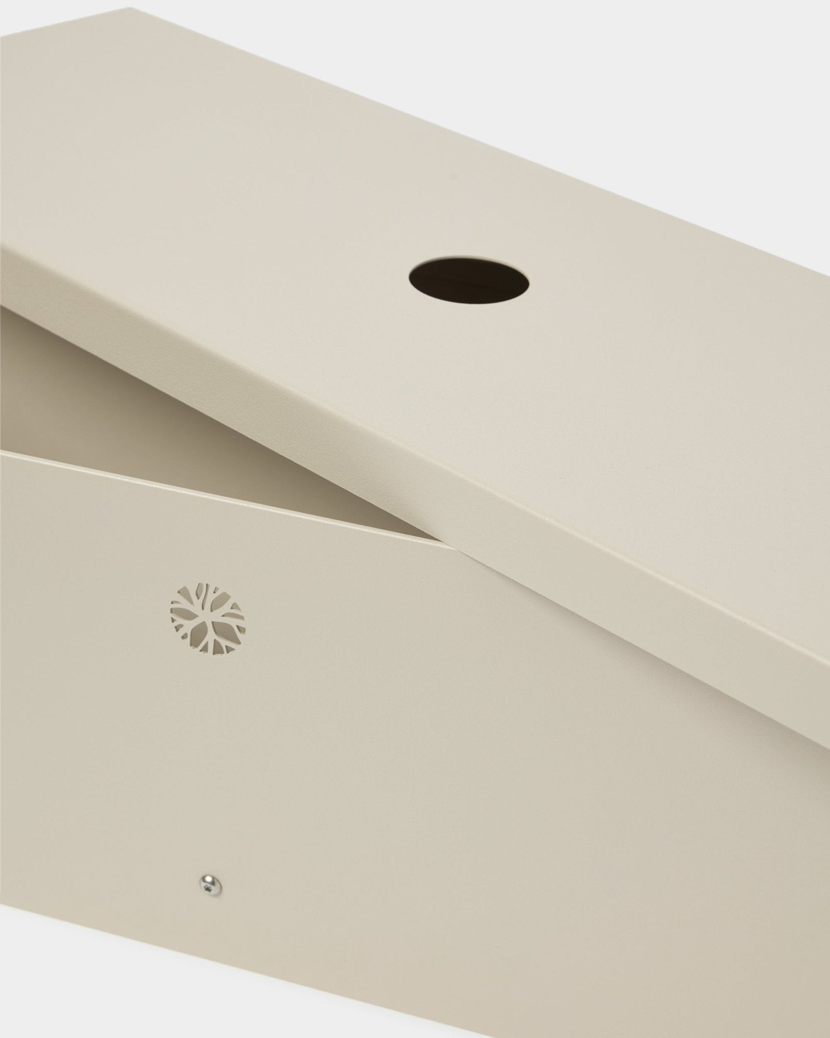 Das Nell | Metal Box / BM2, Beige von WoodUpp besteht aus pulverbeschichtetem steel und hat einen schrägen Deckel, eine runde Öffnung und ein dezentes Emblem an der Seite.
