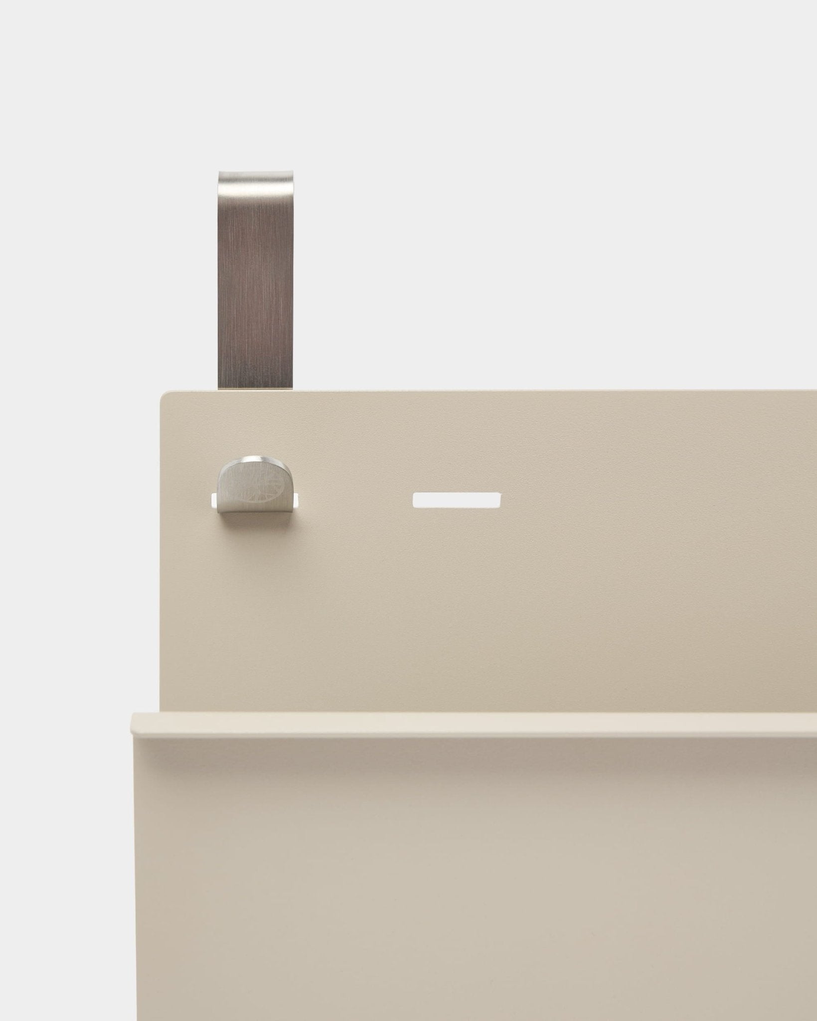 Nahaufnahme des WoodUpp Nell Magazine Storage in beige, pulverbeschichtet in steel, mit Ablage, Schlitz, Schraube und gebogenem Griff; nutzbar als Raumteiler oder Zeitschriftenhalter.