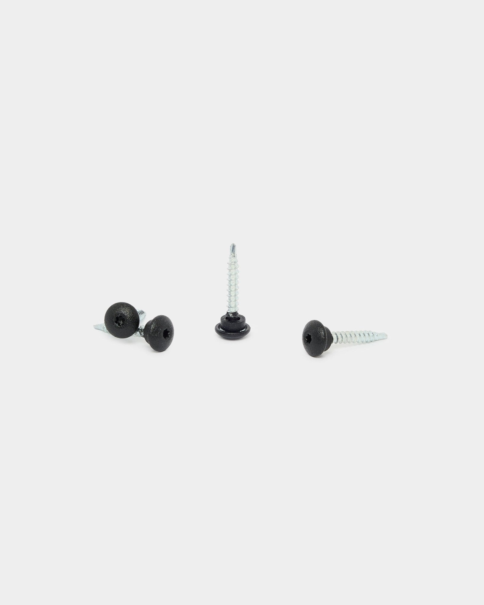 Drei WoodUpp black Front Screws 4.8x35 mit Ø9.5 Unterlegscheiben, entwickelt für Akupanel Akustikpaneele, vor weißem Hintergrund: eine aufrecht, zwei liegend.