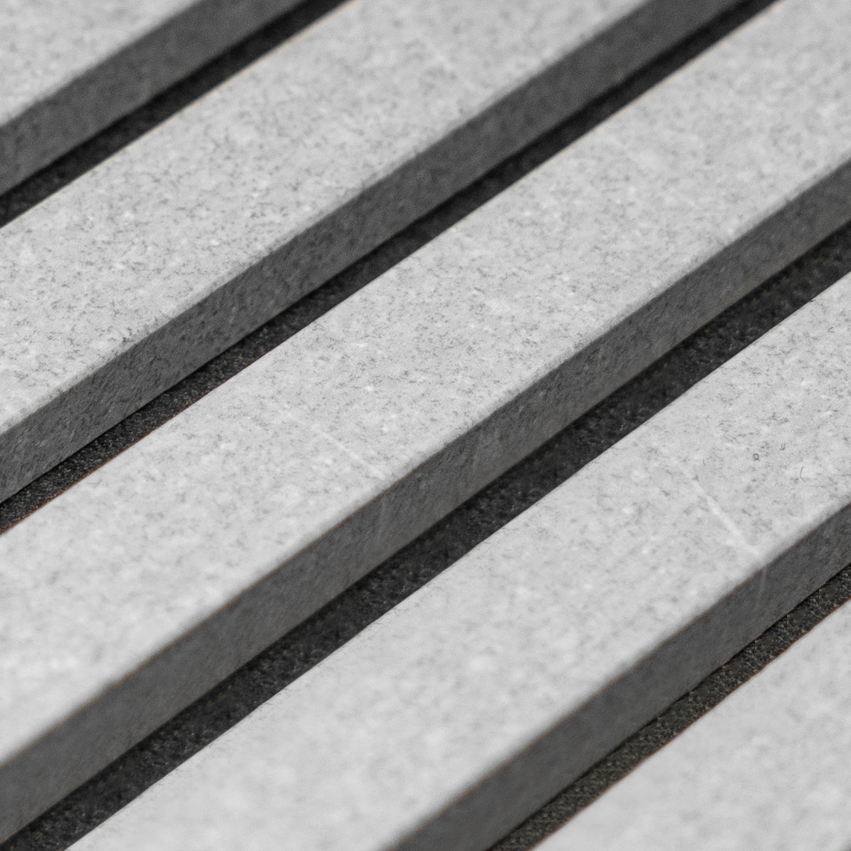 WoodUpp Akupanel im Detail: graue Akustiklamellen aus Beton mit schwarzer Filzrückseite, Maße 240 x 60 cm, angeordnet in einem modernen geometrischen Muster.