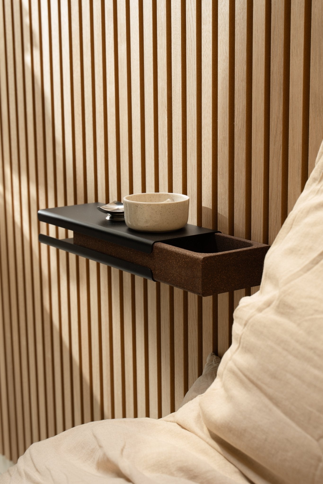 Minimalistisches Wandregal mit einer Keramikschale und WoodUpp Norr Key Tray neben einem beige Kissen und Akupanel Akustikpaneel, beleuchtet von weichem natürlichem Licht.