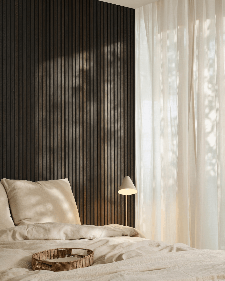Minimalistisches Schlafzimmer mit einem beige Bett, Tablett aus Rattan, Scandi-Akzenten und dem WoodUpp Akupanel Akustik-Holzpaneel in Rustic Smoked Oak, montiert an einer dunklen Wand.