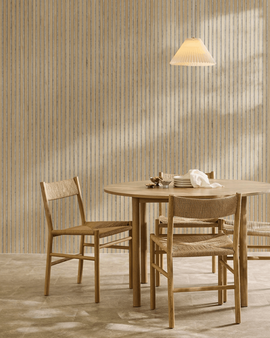 Minimalistischer Essbereich mit rundem Holztisch, geflochtenen Stühlen, einer Pendelleuchte und einem WoodUpp Akupanel Akustik-Holzpaneel in Classic Oak mit grey Filz.