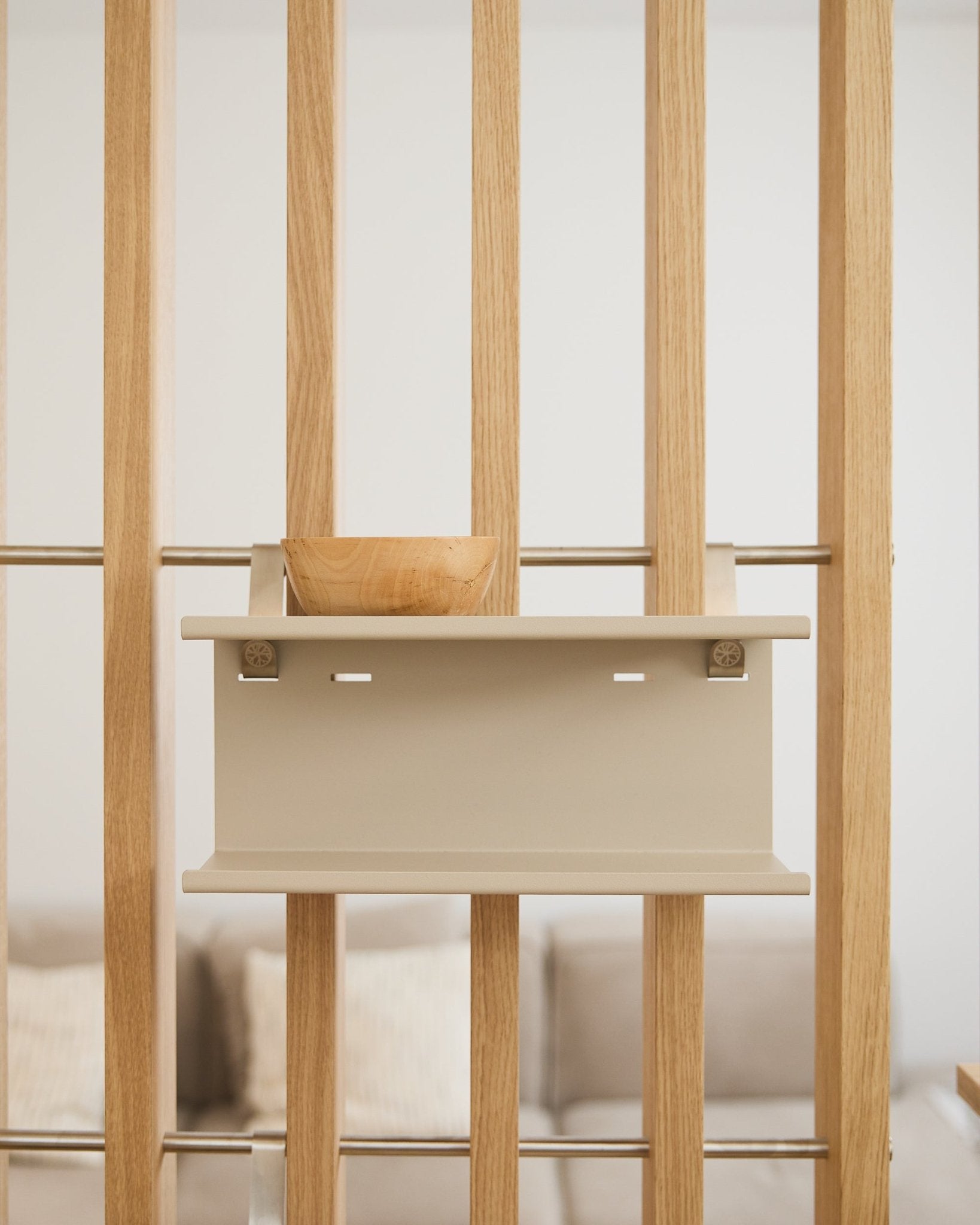 Eine small Holzschale auf dem beige Nell Double Metal Shelf von WoodUpp (31,7 cm), mit einem unscharfen Sofa und Kissen im Hintergrund.